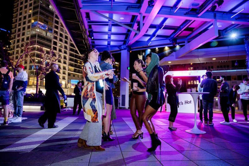 A group of people dance on the floor of The Rooftop Terrace at night.